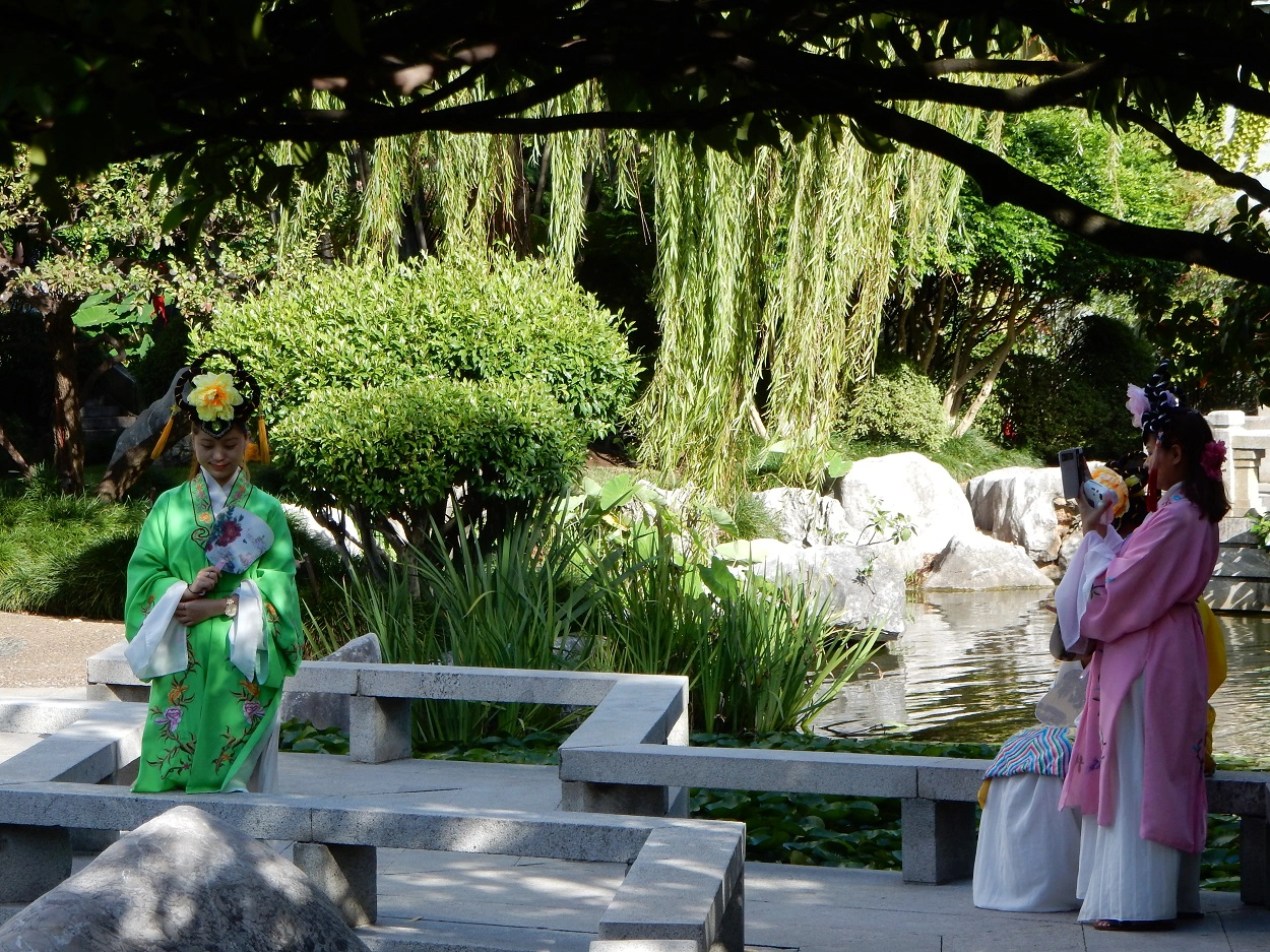 Young Chinese girls in traditional dress taking pictures in the garden